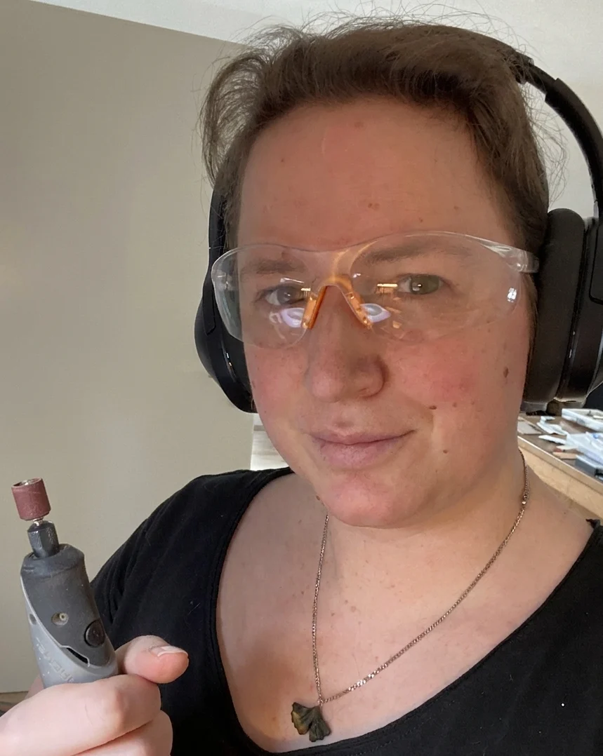 Sonja Ritschmann mit Schleifgerät und Schutzbrille in der Werkstatt, sie trägt eine Ginkgo-Kette